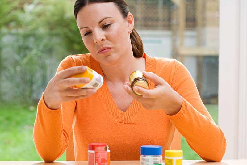 woman reading labels on pill bottles