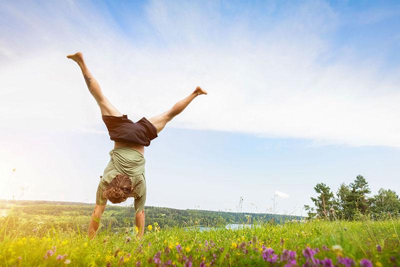 Young man doing a handstand in a grassy field